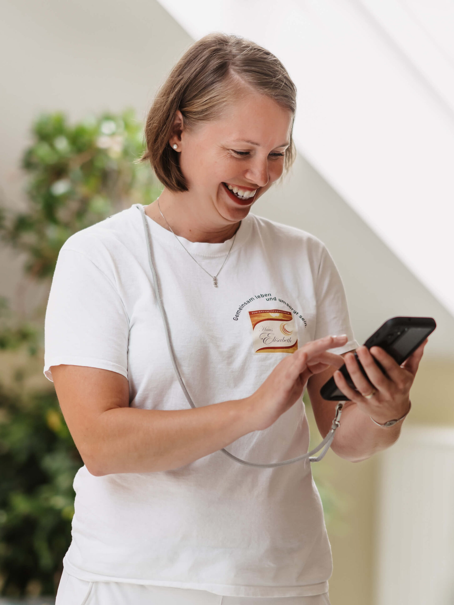 Pflegekraft lächelt und arbeitet mit einem Smartphone