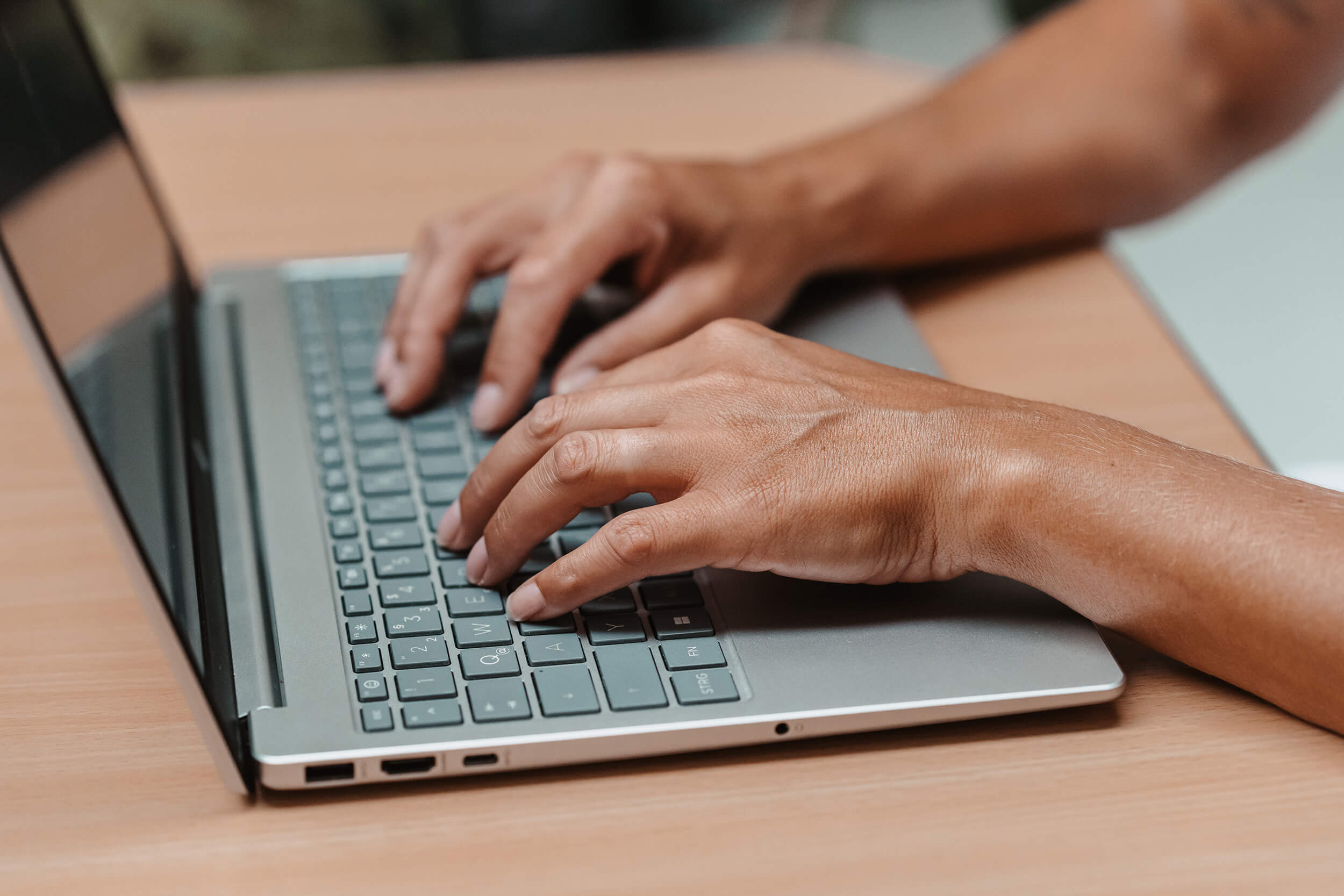 Nahaufnahme von Händen, die auf einem Laptop tippen