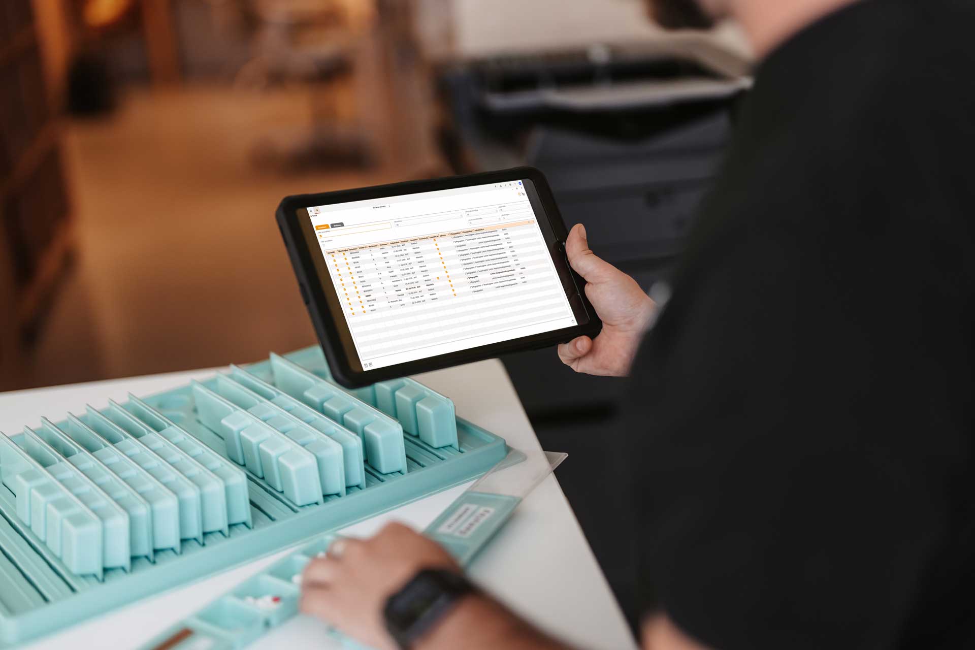 Pflegekraft hält Tablet neben einer Medikamentenbox – Notfallblatt digital abrufbar