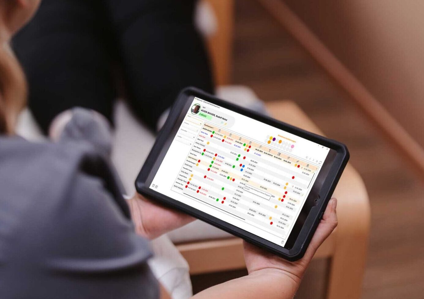 Pflegekraft hält Tablet mit Pflegemonitor und Ampelsystem in der Hand