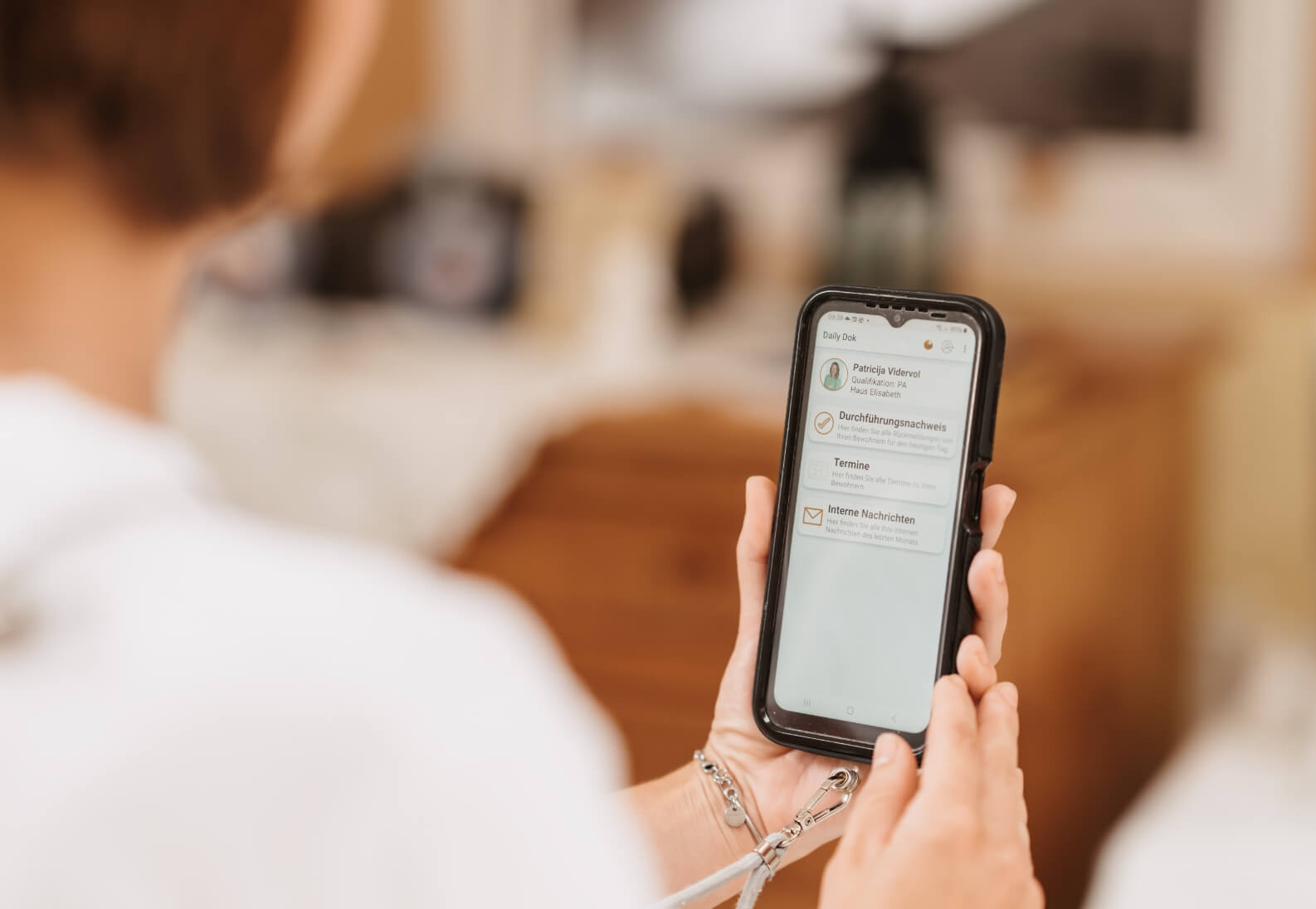 Pflegekraft dokumentiert am Smartphone direkt am Bewohnerbett