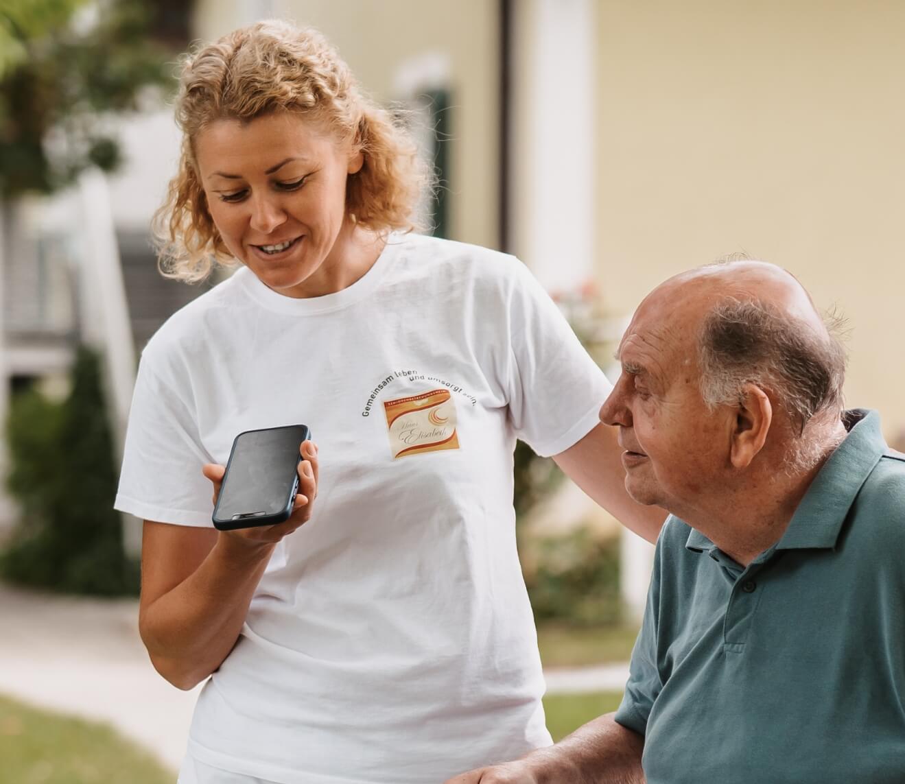Pflegekraft spricht eine Sprachnotiz in ihr Smartphone für die Dokumentation