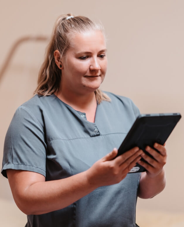 Pflegekraft arbeitet mit einem Tablet im Pflegealltag