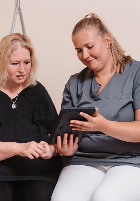 Pflegekraft dokumentiert Informationen während einer Übergabe am Tablet
